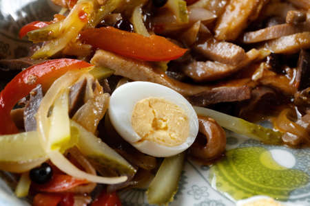 Boiled egg cut in half, lies on a salad of meat and vegetables.の写真素材