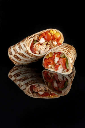 Burritos wraps with beef and vegetables on black background. Beef burrito, mexican food. Vertical photoの写真素材
