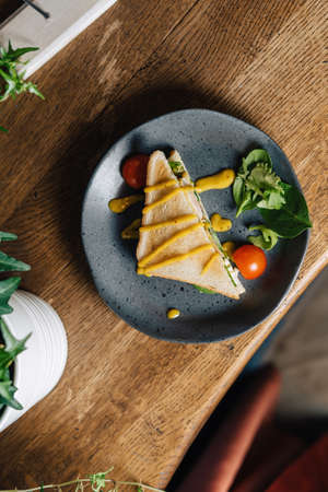 Panini with young spinach leaves, onions and cheese served on a wooden table.