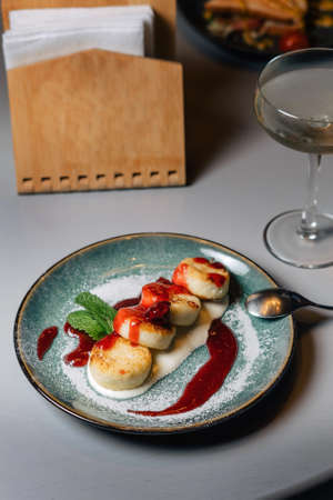 Syrniki, cottage cheese fritters with raspberry jam. Garnished with a mint leaf.の写真素材
