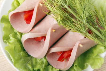 Roll of homemade sausage with vegetables on a wooden backgroundの写真素材