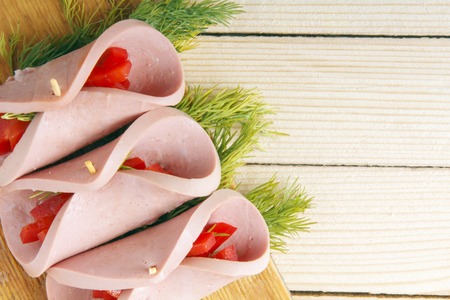 Roll of homemade sausage with vegetables on a wooden background. Space for textの写真素材