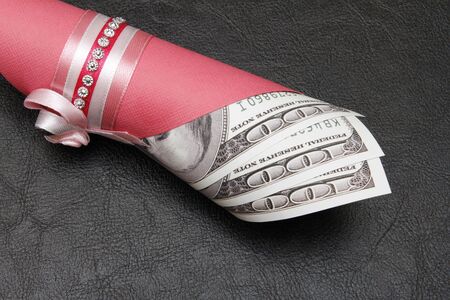 A hundred dollars in a roll on a black background, close-up. There is a place for textの写真素材