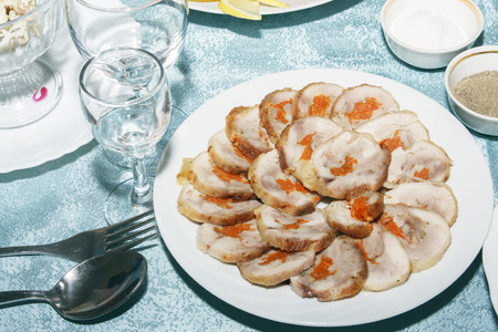 Table served with roll of poultry meat with vegetables filling. Empty clean wine glasses and delicious cold snack on festive table.の写真素材
