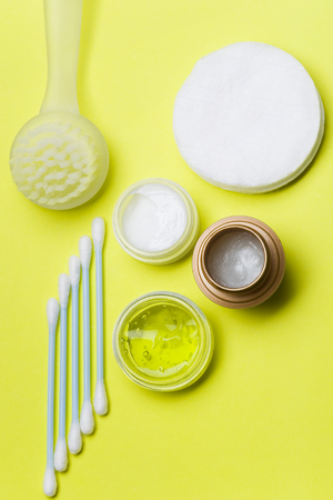 A top view of the items for personal care arrange in a lighte green background. Swabs and cotton pads for face, cream, lip balm, gel and pilling brush.の写真素材
