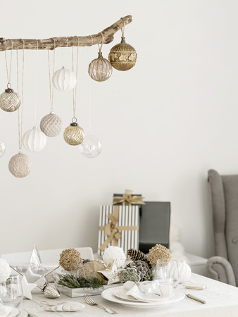 Table served for Christmas, New Year dinner in living room. Plate with linen napkin, napkin holders, pine cones, wine glass. Styled with an old-fashioned decoration in natural colors and stars.の写真素材