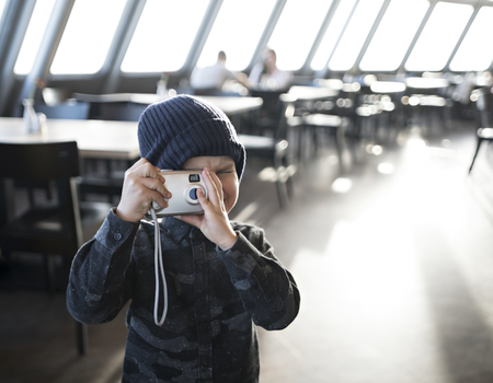 Hipster little boy with his old-school photo camera take a pictures in restaurantの写真素材