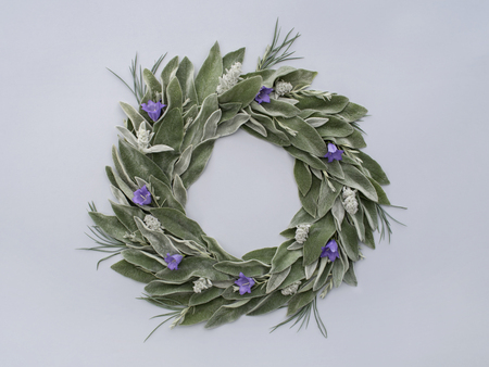 Round frame wreath pattern with green leaves and blue flowers. Top view, flat lay.の写真素材