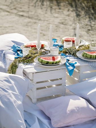 From above shot of table set with elegant utensil and candles and served with watermelon and strawberry on plates.の写真素材
