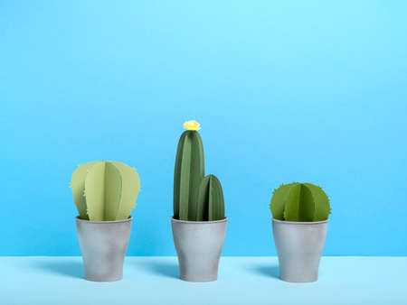 Layout of three-dimensional green paper cactuses in pots composed in row against blue background.の写真素材