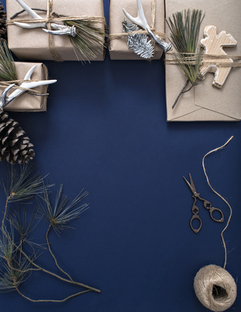 From above shot of composed wrapped craft present boxes with ornamental natural decor on blue background.の写真素材
