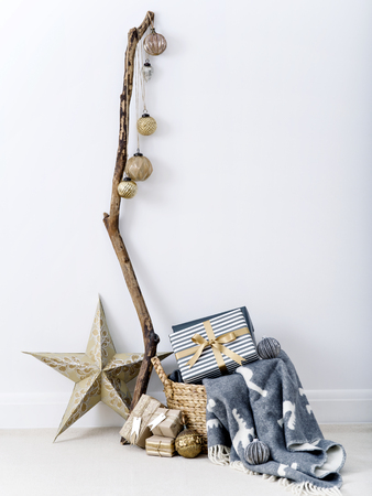 Creative stylish composition with baubles on stick and presents in wicker basket on white background.の写真素材
