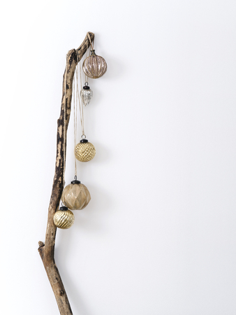 Minimalist composition of wood stick with hanging shiny baubles for Christmas concept.の写真素材