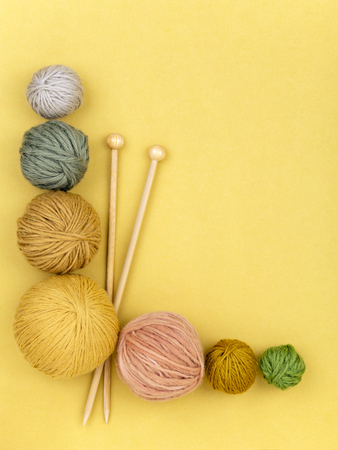 Wooden needles and set of various yarn rolls lying on yellow background.の写真素材