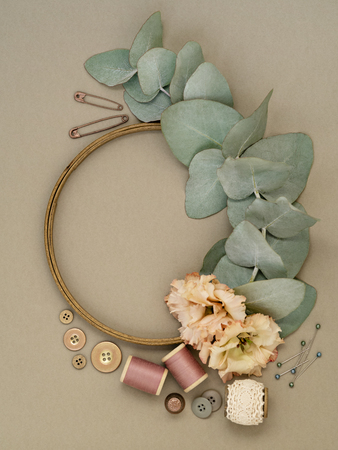 Beautiful flowers and leaves lying in various tools for embroidery on gray background.の写真素材
