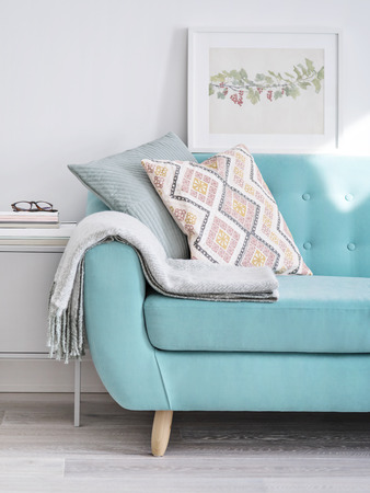 Vibrant sofa decorated with cushions and woolen plaid in bright sunlit room with minimal design. Living Room concept.の写真素材