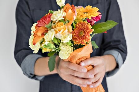 Faceless man holding beautiful arrangement of colorful bright flowers on white background.の写真素材