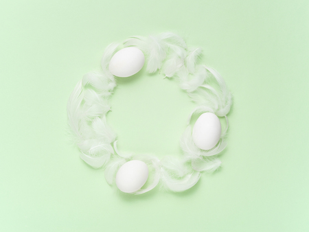 Light and pure Easter background. Feather and eggs wreath on a green pastel background. Easter decoration concept.の写真素材