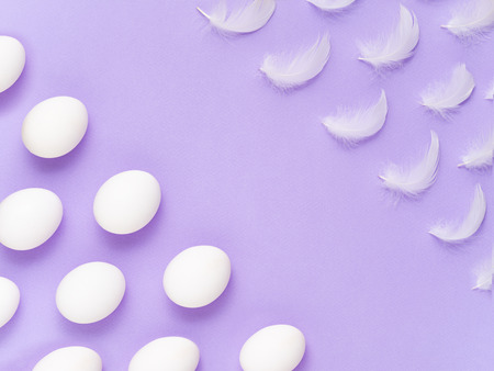 Diagonally oriented rows of fluffy white feathers and chicken eggs. Easter Holiday mood. Purity and lightness concept background.の写真素材