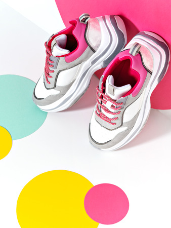 Bright lit scene with chunky sneakers and huge confetti. Colorful casual wear or footwear. Minimalist fashion fitness creative concept.の写真素材