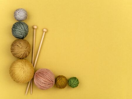 Wooden needles and various color balls of yarn on yellow background. Craft, knitting or hand made concept. Winter hobby frame. Top view, flat lay. Horizontal image.の写真素材