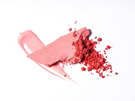 Pale pink beauty and makeup products composition. Top view of spills and smears of lip gloss, flipstick and shimmering powdered blush isolated on white background. Beauty, professional makeup, fashion concept. Flat lay.の写真素材