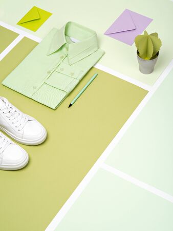 Mint green plain cotton formal shirt, white sneakers, envelopes, pencil and artificial paper succulent arranged on a various green paper background. Work outfit  or minimalist office concept background with copy space.の写真素材