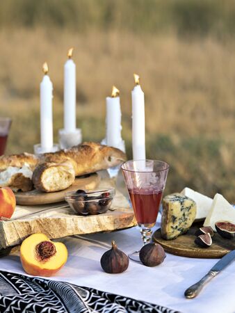Close up shot of a summer brunch or dinner organized on a sea shore for friends.  Elegant place decorated  in black and white tones for romantic date. Fruits, cheese, olives and bread as a light snacks for summer camping date or picnic.の写真素材