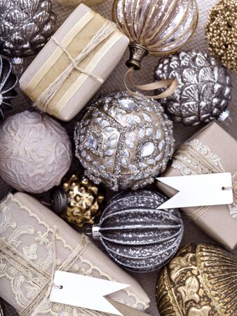 Flat lay composition of stylish vintage silver and gold Christmas balls and charming wrapped gifts with blank tags. Winter holidays background, New Year and Christmas decoration.の写真素材