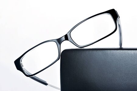 Stylish black eyewear diagonally laid on leather case. Classic accessory for reading.の写真素材