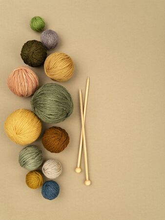 Various size and color balls of yarn arranged in a row as left frame with wooden knitting needles. Craft, knitting or hand made concept. Winter hobby background. Top view, flat lay, copy space for text.の写真素材