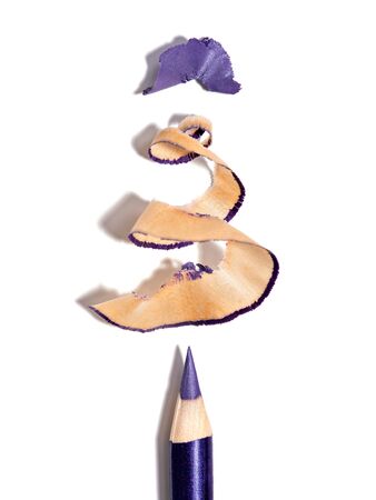 Violet eye pencil and its shavings shaped as a Christmas tree, isolated on white backdrop. Creative makeup background. Winter holidays mood. Concept photo of eye makeup, cosmetics, beauty products.の写真素材
