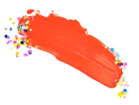 Brushstroke of coral pink paint and various color confetti isolated on white background. Creative festive background.の写真素材