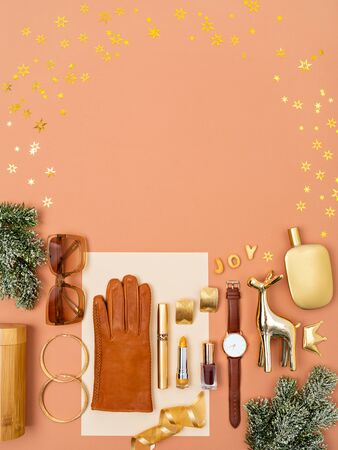 Christmas objects and gifts laid out as a bottom frame decorated with golden sequins. Feminine accessories and cosmetics as a gifts guide for her. Flat lay, top view. Copy space for text.の写真素材