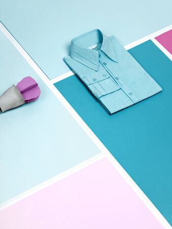 Trendy ocean-blue plain cotton formal shirt and artificial purple paper succulent on a mosaic blue and pink background. Work outfit or minimalist office concept background with copy space.の写真素材