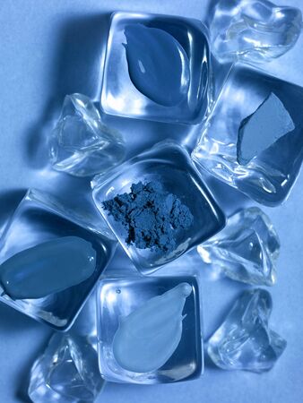 Samples of different blue makeup products on artificial ice cubes. Classic blue face makeup, cooling cosmetics concept. Main color trend. Color of the year 2020 classic blue background.の写真素材