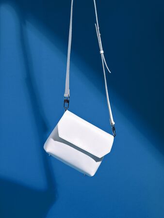 Levitating female white sneakers and small stylish cross body bag on deep classic blue background. Minimalist stylish female accessory.  Color of the year 2020. Main color trend. Summer sale concept.の写真素材