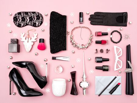 Black and red feminine accessories, cosmetics and Christmas decoration on pink background. Gifts guide for her. Flat lay, top view.の写真素材