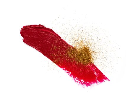Vibrant wine red lipstick smear with spilled golden glitter isolated on white backdrop. Sample of cosmetics. Closeup of a smudged makeup. Makeup texture.の写真素材