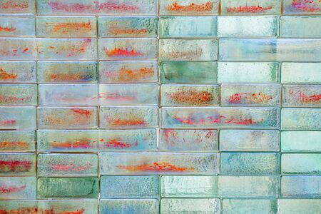 Abstract background of shiny glass bricks. Mosaic texture, abstract geometric pattern. A colourful glass blocks wall backdrop. Structured surface. Architecture, interior.の写真素材