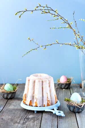 Easter cake and coloured eggs minimalist composition on a wooden table. Easter decoration for...