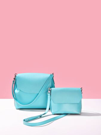Studio shot of two glamorous Turquoise blue leather bags on pink background. Trendy Summer Accessories. Fashion industry, modern female concept.の写真素材