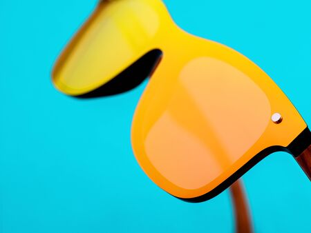 Minimal style closeup photography of  orange mirror sunglasses on blue background. Minimalist summer...