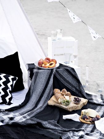 Summer brunch or dinner organised on a sea shore for friends. Elegant place decorated  in black and white tones for romantic date. Light snacks for summer camping date or picnic.の写真素材