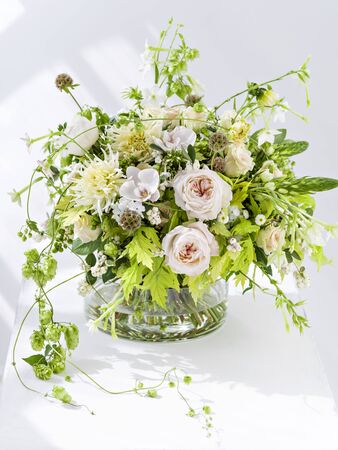 Beautiful boho flowers bouquet in interior.  Green hops, yellow chrysanthemum and pastel pink roses.の写真素材