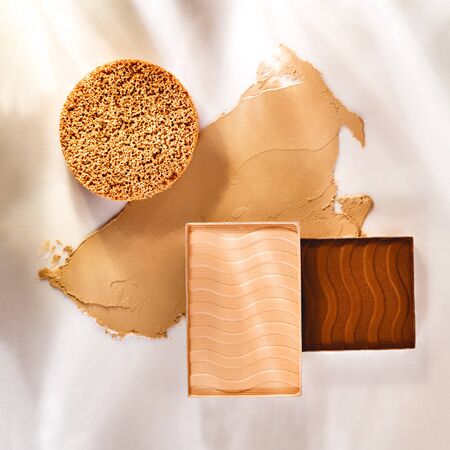 Still life of beauty products with soft light and shadows. Composition of smudged and scattered makeup texture. Closeup of nude makeup products for makeup artists.の写真素材