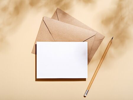 White empty card with stationery set of envelopes, notebook, pencil. Blank card styled mockup with hard light and shadow. To do list, greeting card or writing a letter concept.の写真素材