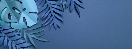 Minimalist composition of amazing blue tropical leaves made of craft paper on blue backdrop. Summertime mood. Flat lay with cut out paper palm, monstera leaves. Exotic floral frame with copy space.の写真素材