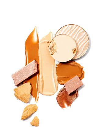 Makeup products of natural shades. Spills and smears of makeup foundation, broken eyeshadow and face powder isolated on white background. Beauty, professional makeup, contouring, fashion concept.の写真素材