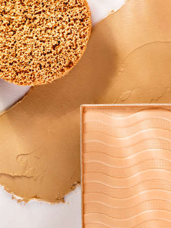 Still life of beauty products with soft light and shadows. Composition of smudged and scattered makeup texture. Closeup of nude makeup products for makeup artists.の写真素材